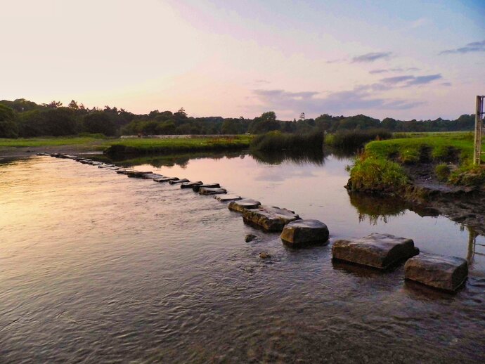 A photo of stepping stones across a lake at sunset