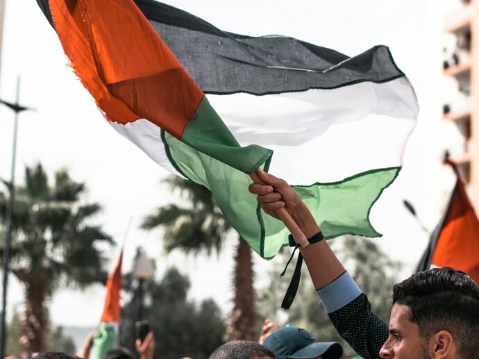 A man holding aloft a palestinian flag