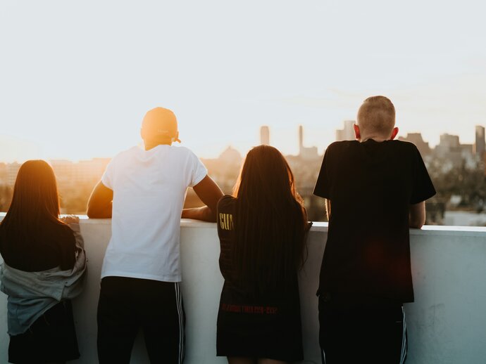 a racially diverse group of  young people standing looking out at a cityscape