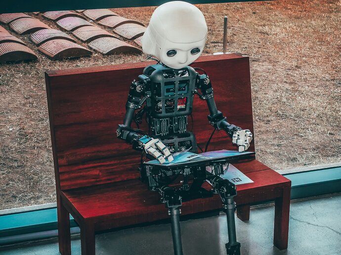 A cute little humanoid robot holding a digital book