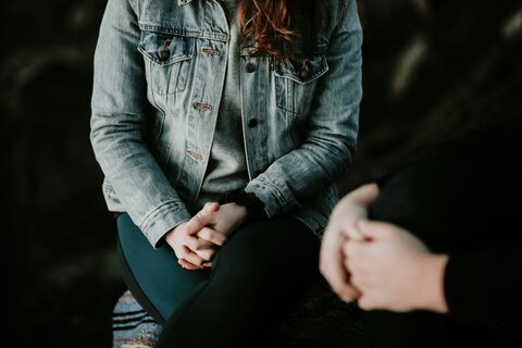 two women sitting across from each other with hands folded in their laps