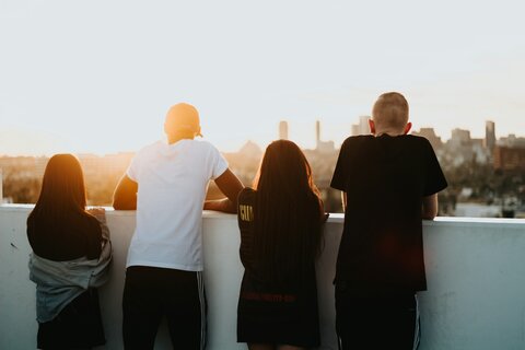 a racially diverse group of  young people standing looking out at a cityscape